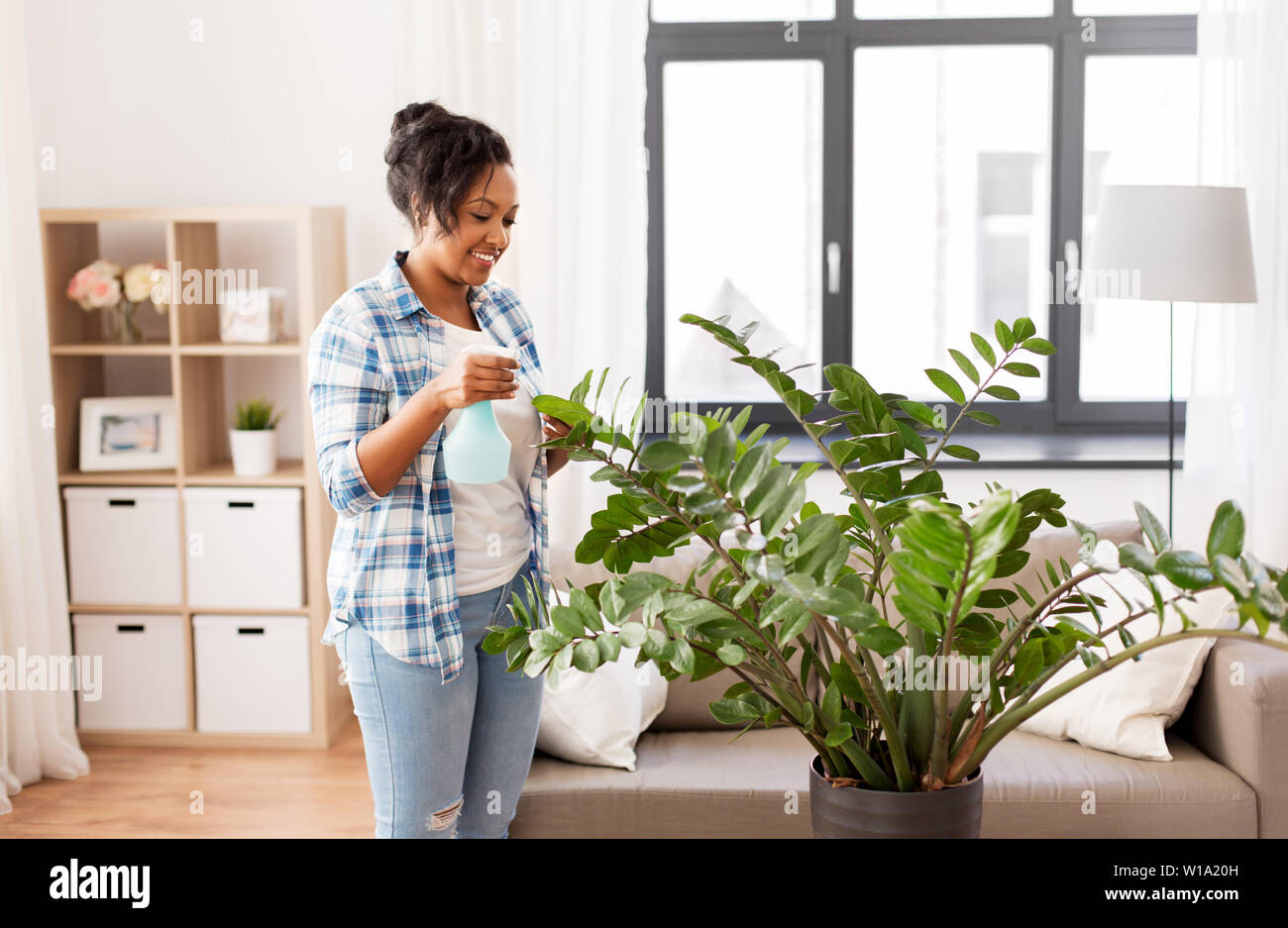 Gerne afrikanische Frau Sprühen Zimmerpflanzen zu Hause Stockfoto