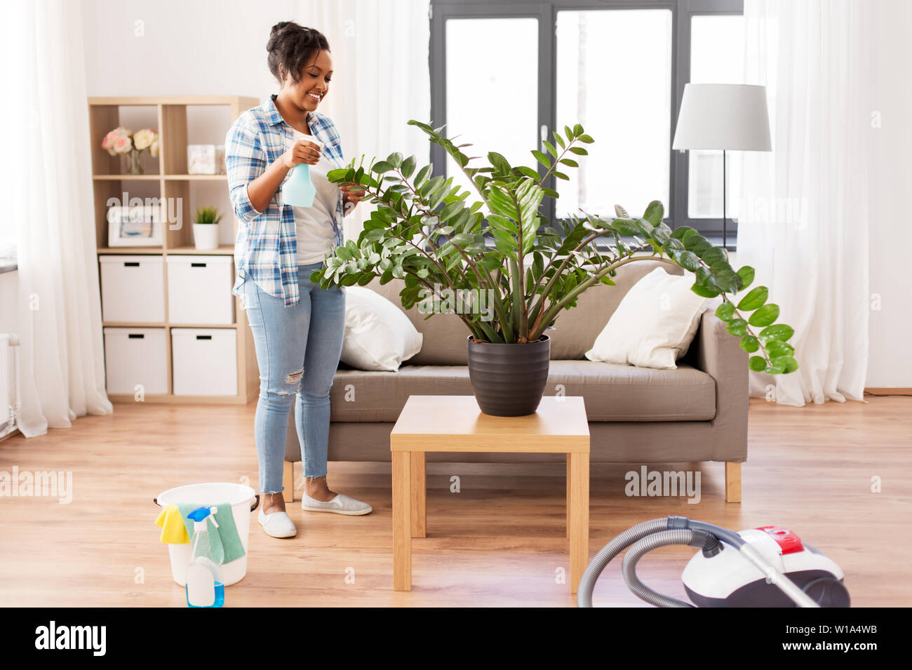 Gerne afrikanische Frau Sprühen Zimmerpflanzen zu Hause Stockfoto