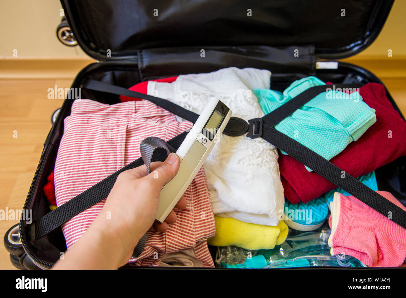 Frau Verpackung digitale Kofferwaage im Gepäck von Übergewicht Gepäck in Flughafen Konzept zu vermeiden. Reduzieren Sie Stress. Stockfoto