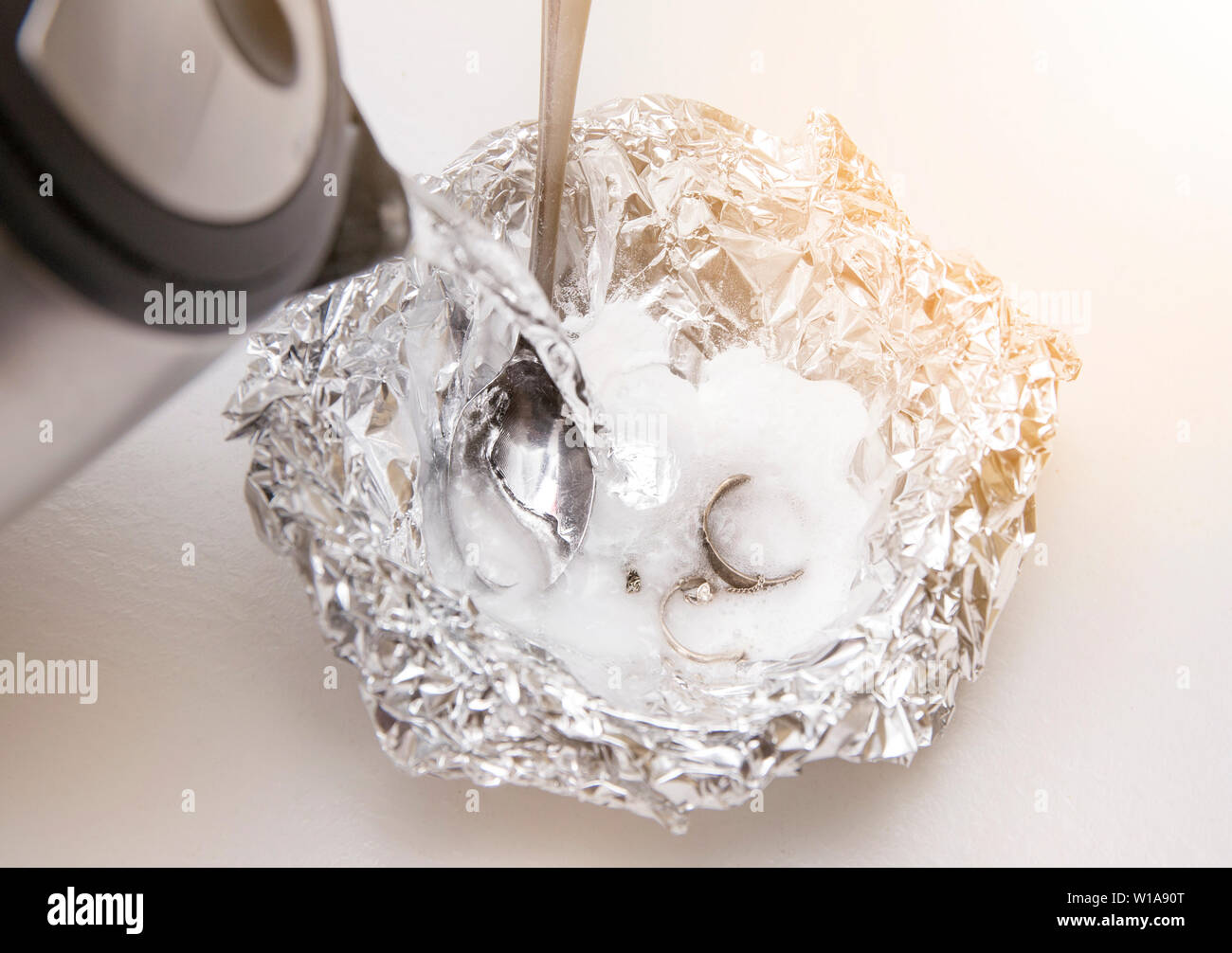 Eine Lösung aus Natron (Natriumbicarbonat) und warmem Wasser entfernen wird die Verfärbung von Silber, wenn das Silber ist in Kontakt mit einem Stück Alumini Stockfoto Eine Lösung aus Natron (Natriumbicarbonat) und warmem Wasser entfernen wird die Verfärbung von Silber, wenn das Silber ist in Kontakt mit einem Stück Alumini Stockfoto