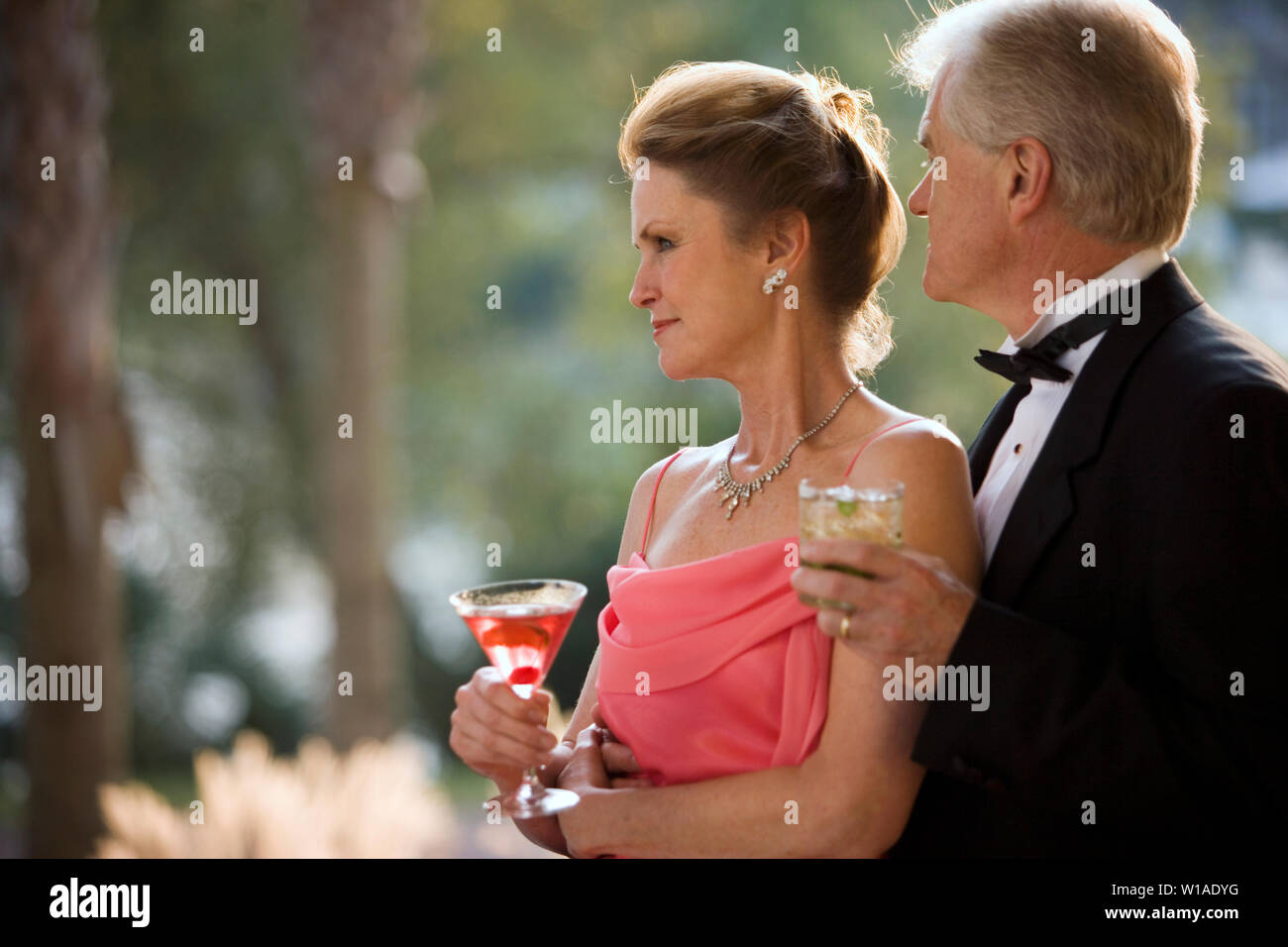 Reifen erwachsenen Paar formell gekleidet Zuneigung zeigen und dabei Cocktails. Stockfoto