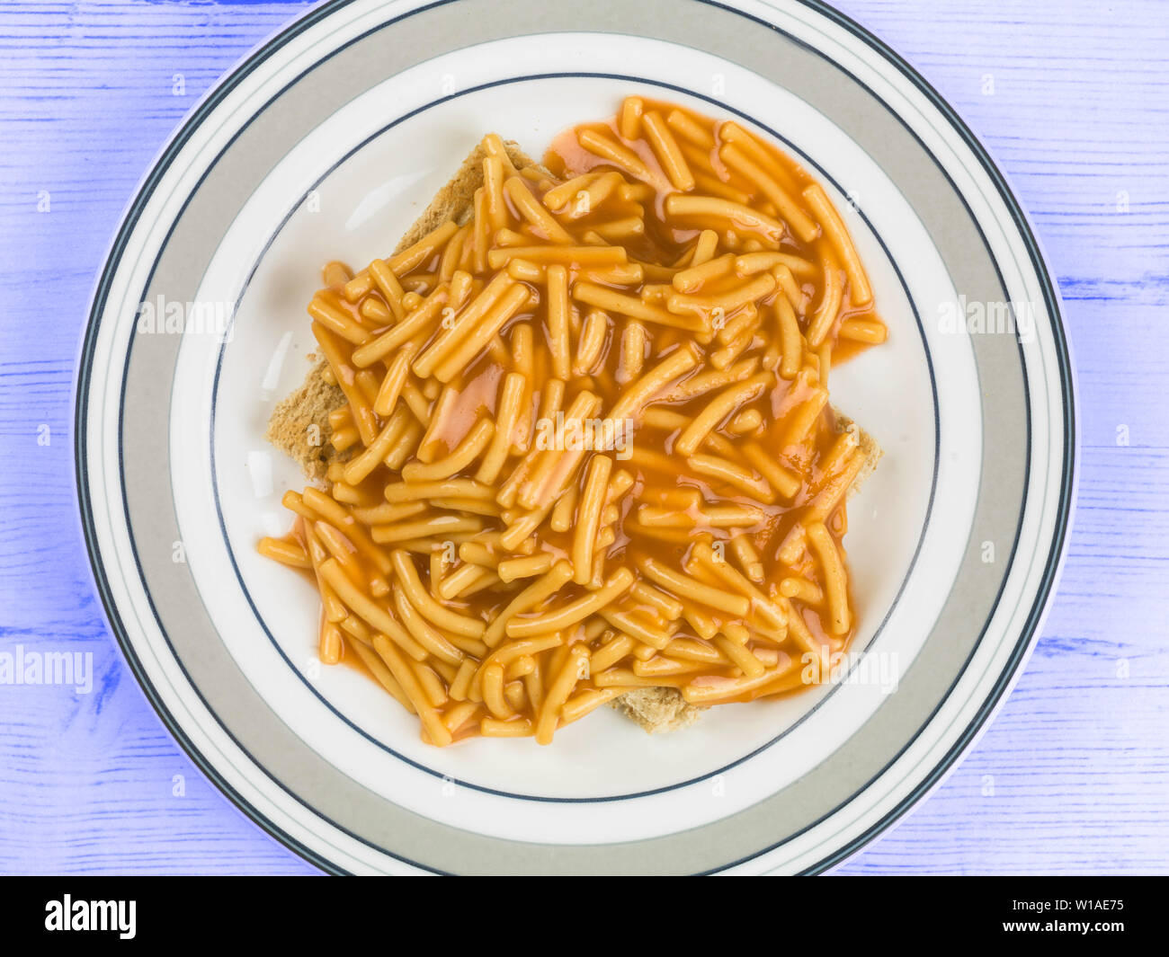 Aus der Dose Spaghetti in Tomatensoße auf geröstetem Brot auf Teller serviert Stockfotografie