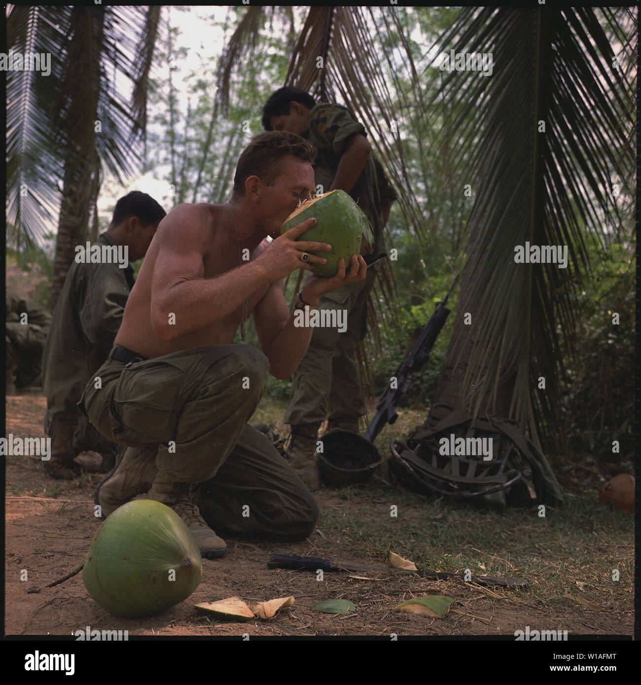 Eine Durchsuchung und Beschlagnahme Phase des Pershing in der Ortschaft Troun Lan, Provinz Binh Dinh, ca. 90 km nordöstlich von Khe. Sergeant George Nemosbatho (Detroit, MI), mortar Platoon Squad Leader, 1.Bataillon, 12 Regiment, 1st Cavalry Division (Airmobile), nimmt einen Schluck frischer Kokosmilch während einer Pause bei der Suche nach dem Feind. Stockfoto