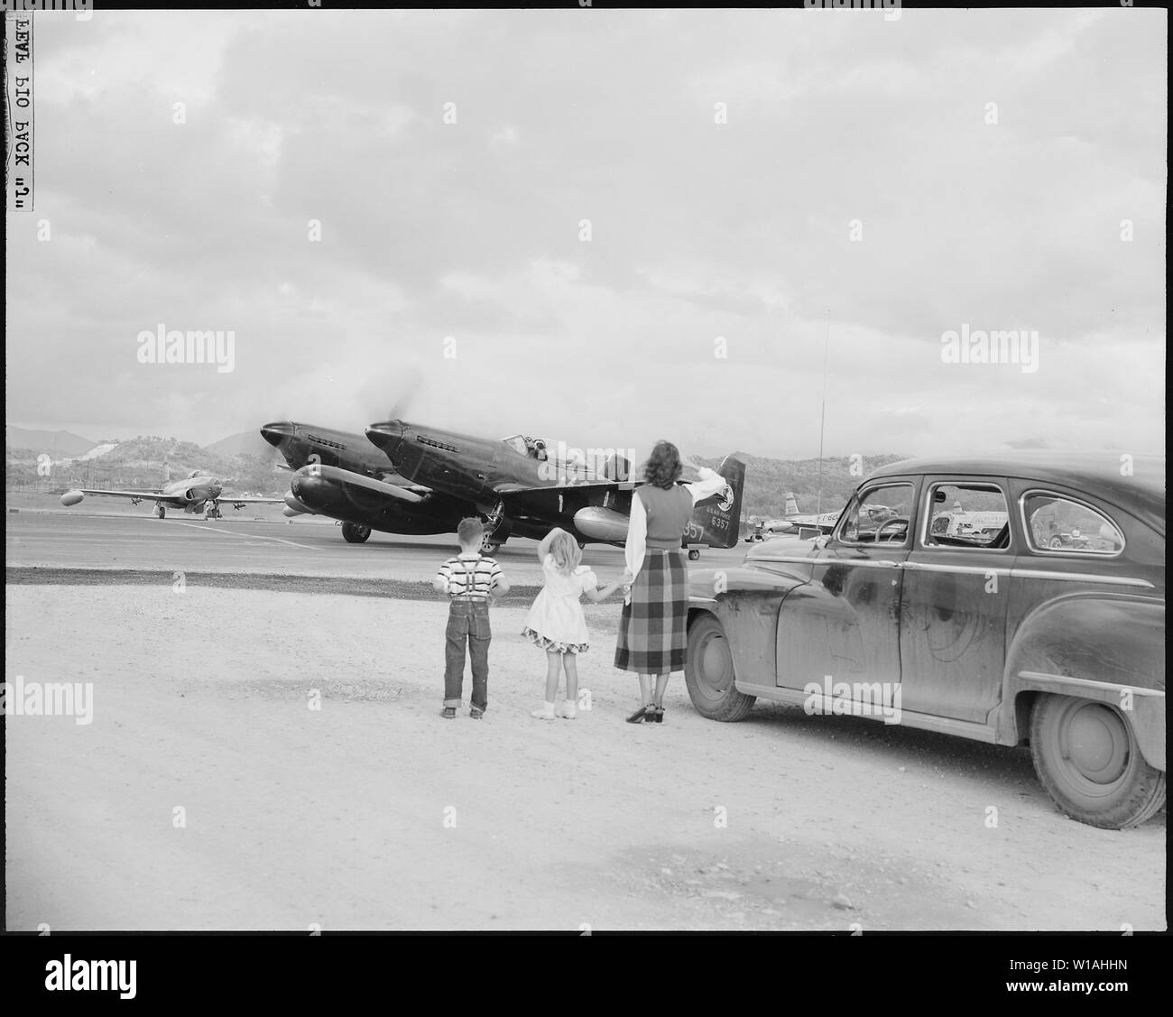 Luftkrieg in Korea. Einen herzlichen Abschied von seiner Familie, sendet Kapitän Johnnie Gosnell Borger, Texas, auf eine weitere Mission in Korea. Waving Goodbye auf dem Feld in der Nähe von Ihrem Haus sind Bill, 6, Sharon, 5, und Frau Gosnell. Gosnell ist ein Pilotprojekt mit dem 68Th All-Weather Fighter Interceptor Squadron in einem fortgeschrittenen US-Fernen Osten Luftwaffen base im Südlichen Japan fliegen. Er bekommt hier bereit, in seinem 2-motorige F-82 Mustang. Stockfoto