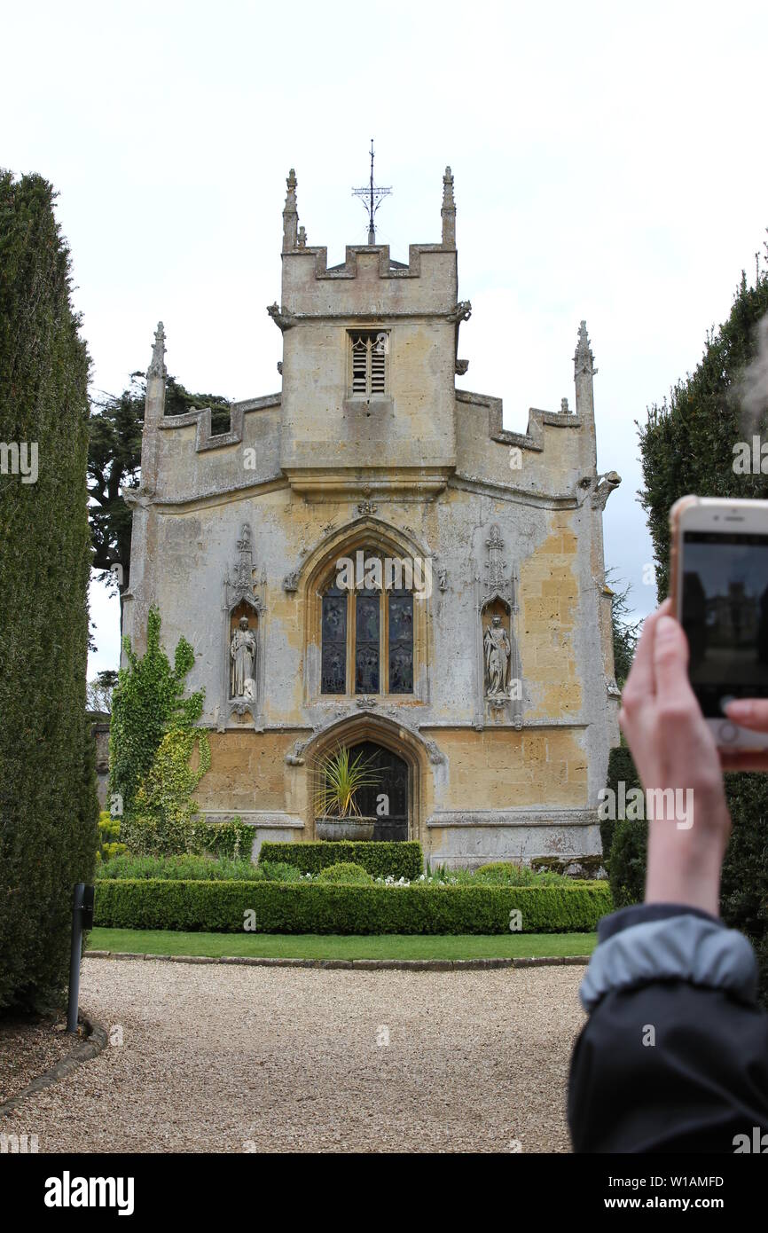 Ein Tourist nimmt ein Bild mit Ihrem Handy von Katherine Parr's Chapel auf dem Gelände des Sudeley Castle in Winchcombe, Gloucestershire, UK. Stockfoto