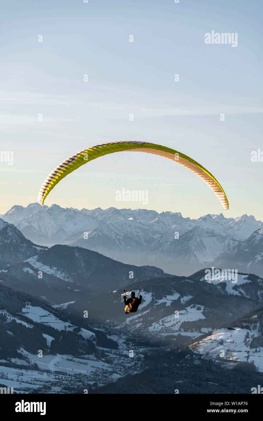 Paragliding in der Luft vor schneebedeckten Alpen im Winter überdacht, Brixen im Thale, Tirol, Österreich Stockfoto