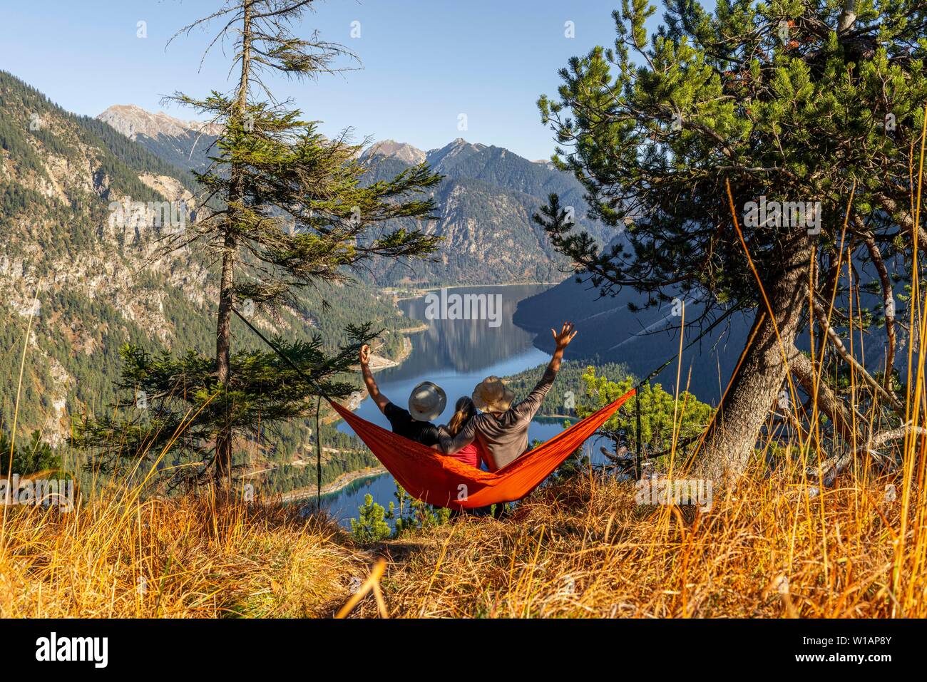 Drei Wanderer sitzen in Hängematten mit Blick auf Berge und See, Plansee, Ammergauer Alpen, Bezirk Reutte, Tirol, Österreich Stockfoto