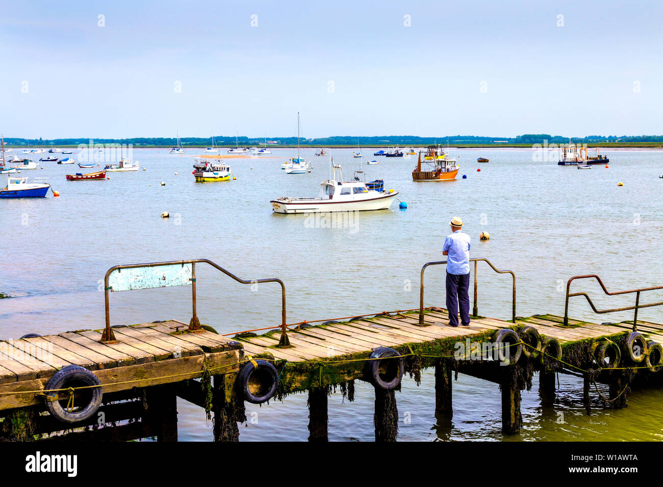 Älterer Mann steht auf einem Pier in der Nähe von Felixstowe Ferry Boat Yard, Suffolk, Großbritannien Stockfoto