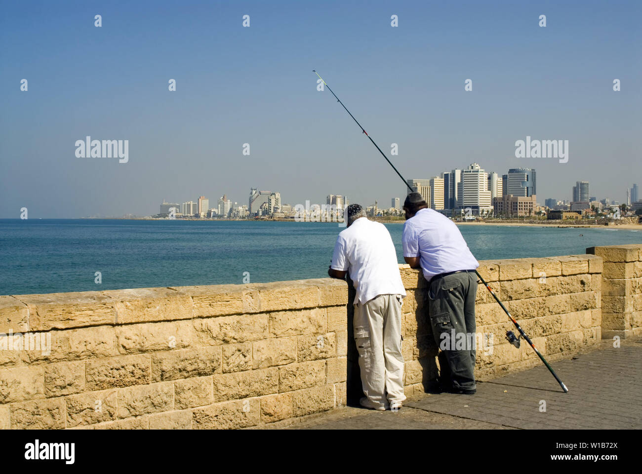 Zwei angeln Mann, lehnen sie an der Wand gegen Tel Aviv anzeigen Stockfoto
