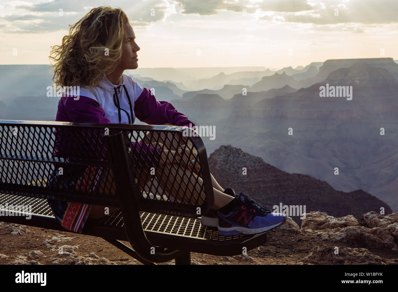 Kaukasische, lockigen Haaren touristische Frau Profil ansehen Sonnenuntergang von einer Bank in Desert View, Grand Canyon National Park, Arizona, USA Stockfoto