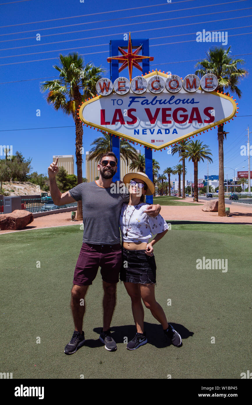 Kaukasische heterosexuellen Paaren, die ein mittleres Alter von 30 Jahren, die unter "Willkommen im fabelhaften Las Vegas'-Zeichen, Las Vegas, Nevada, USA Stockfoto