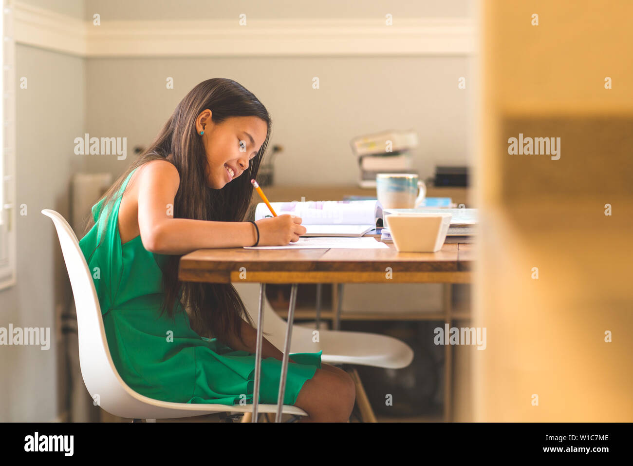 Junges Mädchen sitzt an einem Schreibtisch und arbeitet auf Ihre Hausaufgaben Stockfoto