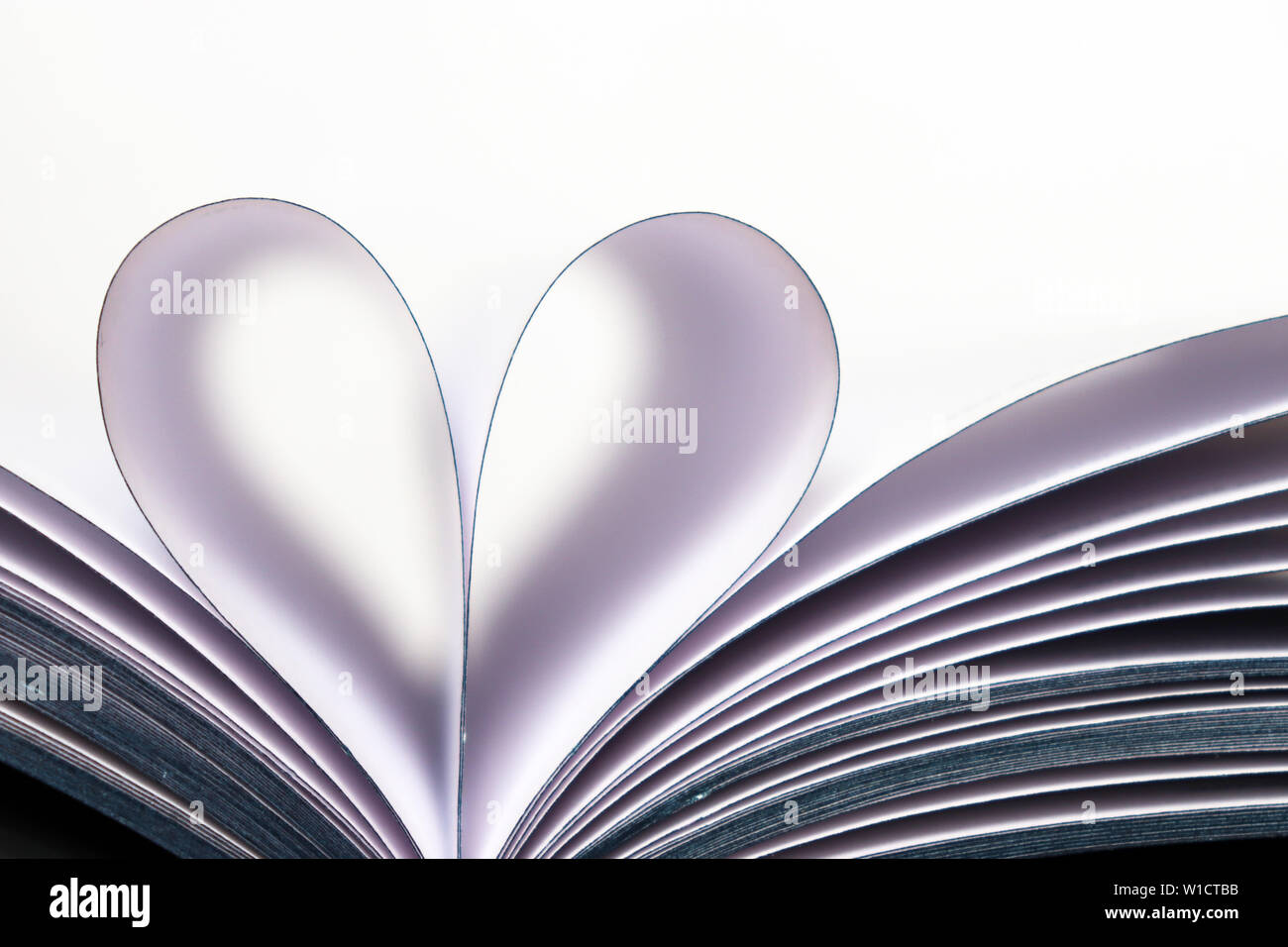 Buchen Sie Seiten geöffnet, in Herzform auf weißem Hintergrund. Liebe zum Lesen, Begriff der Wissenschaft, lernen, Romantik Stockfoto