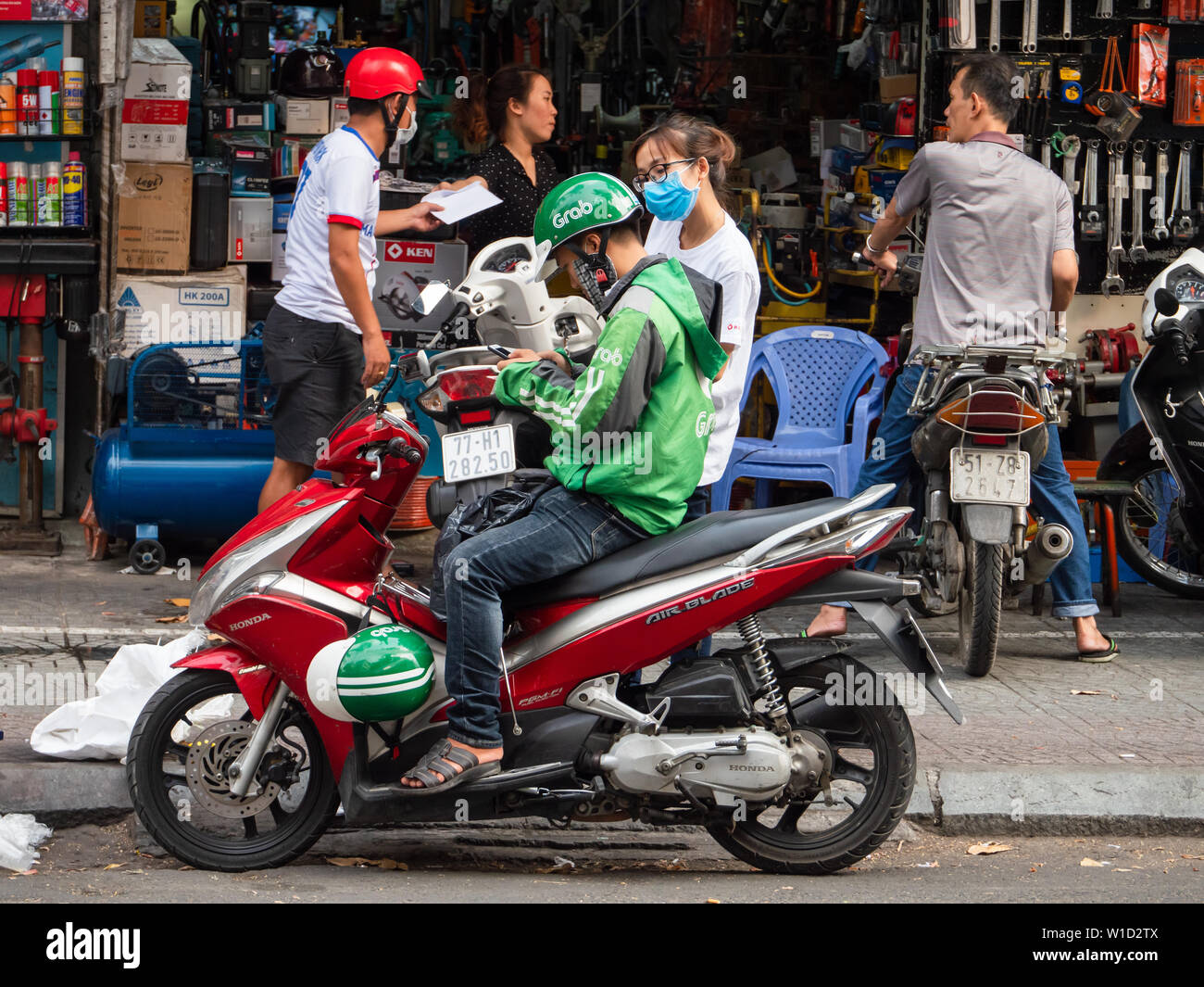 Ho Chi Minh City, Vietnam - April 3, 2019: Zupacken Motorrad Taxi driver Kontrolle der Bestimmung auf seinem Mobiltelefon vor Annahme einer Fahrt in Ho Chi M Stockfoto