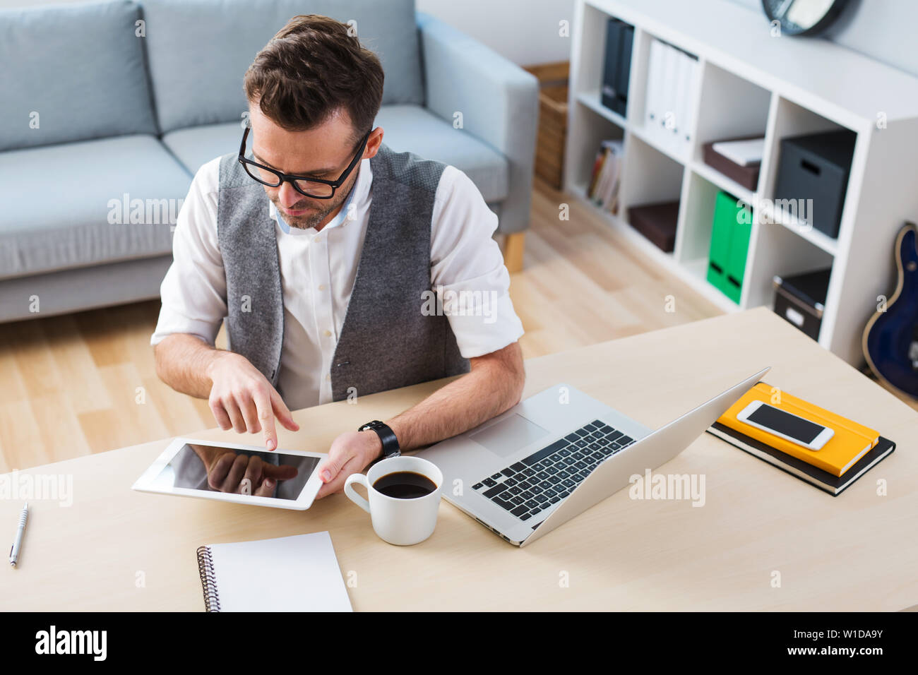 Selbständigkeit - Mann mit digitalen Tablet-PC von zu Hause aus arbeiten Stockfoto