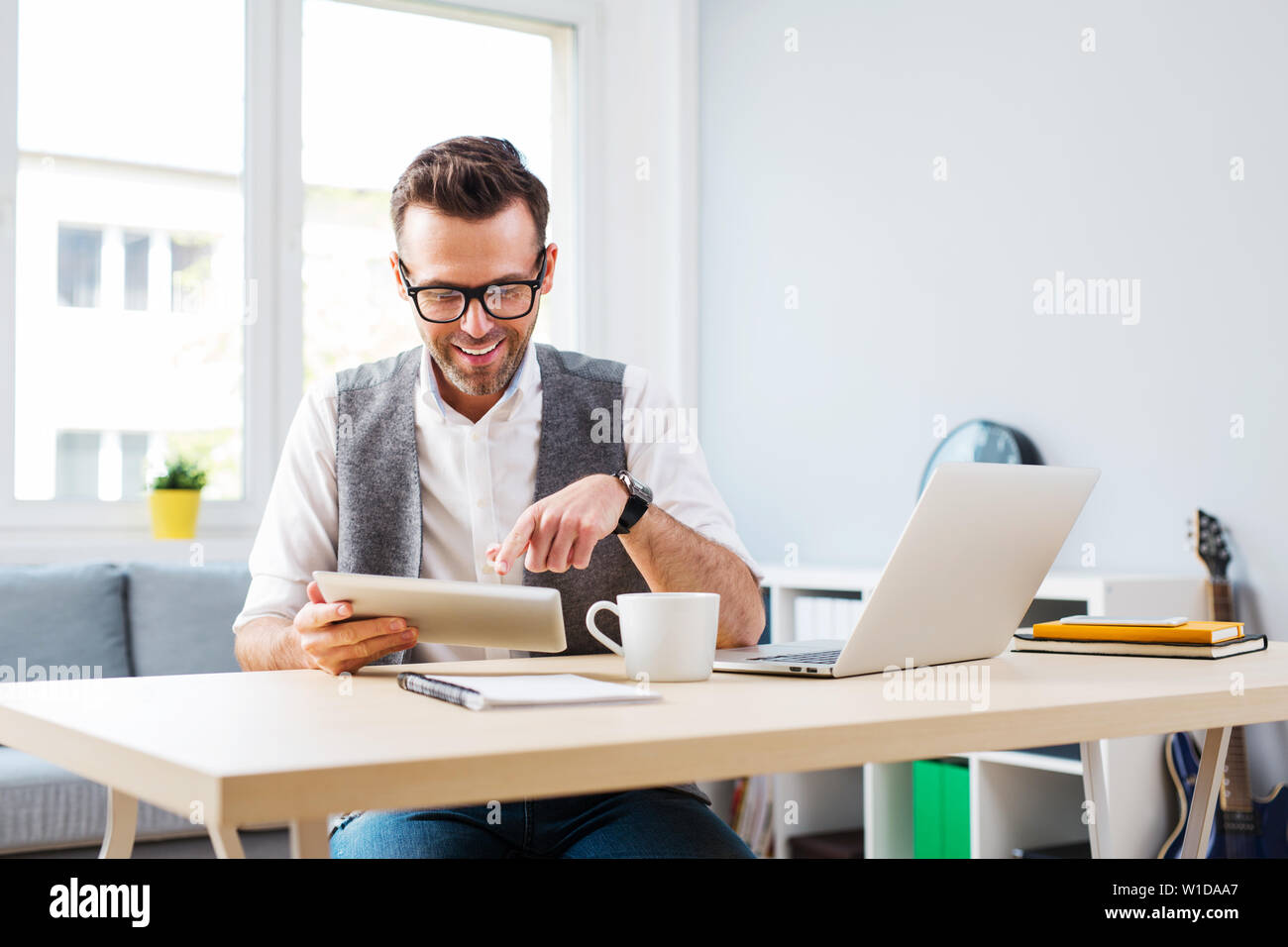 Glückliche Menschen arbeiten von zu Hause aus auf digitalen Tablet-PC und Laptop Stockfoto