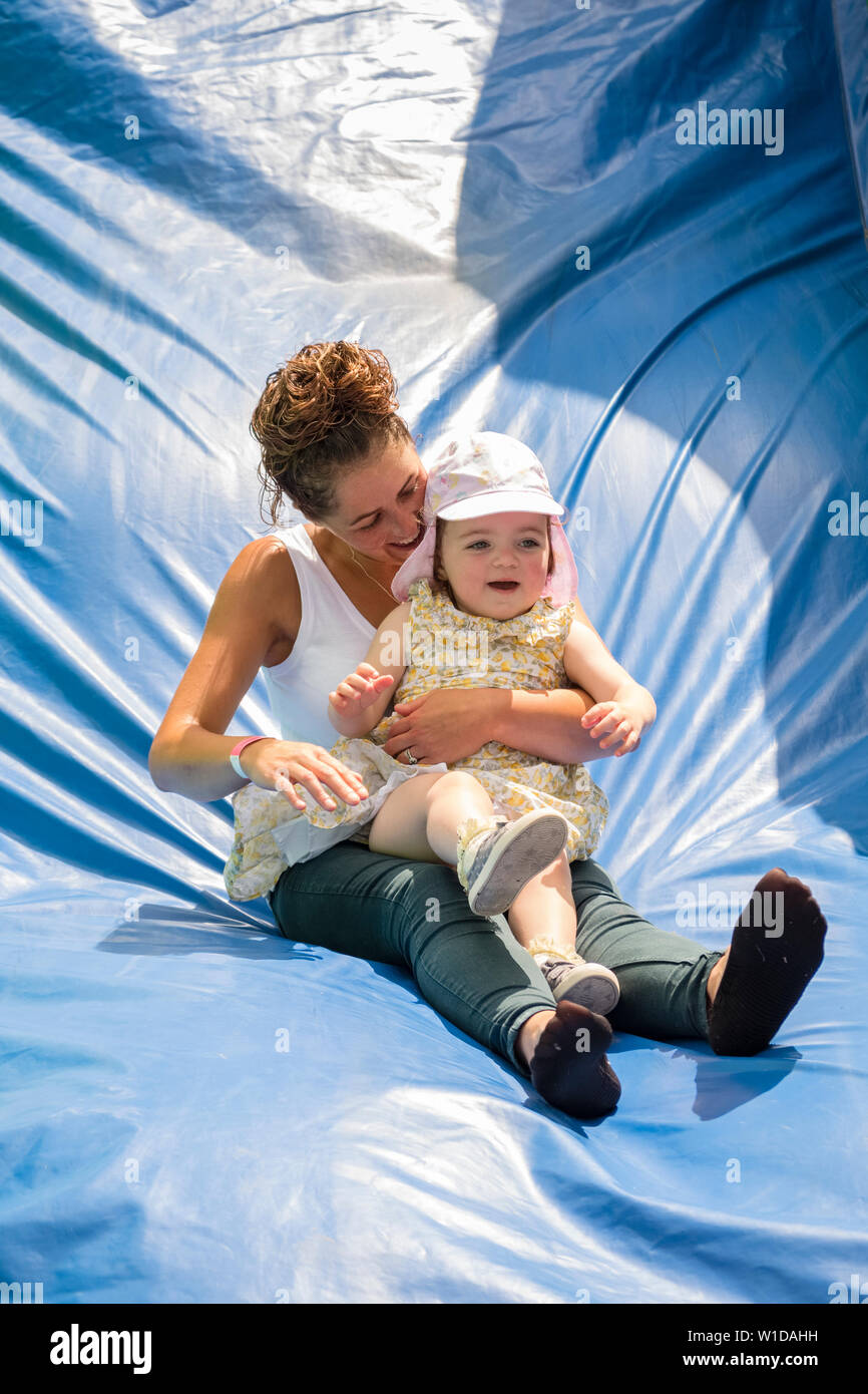 Mutter und Kind Spaß auf einer Hüpfburg Rutsche, Großbritannien Stockfoto