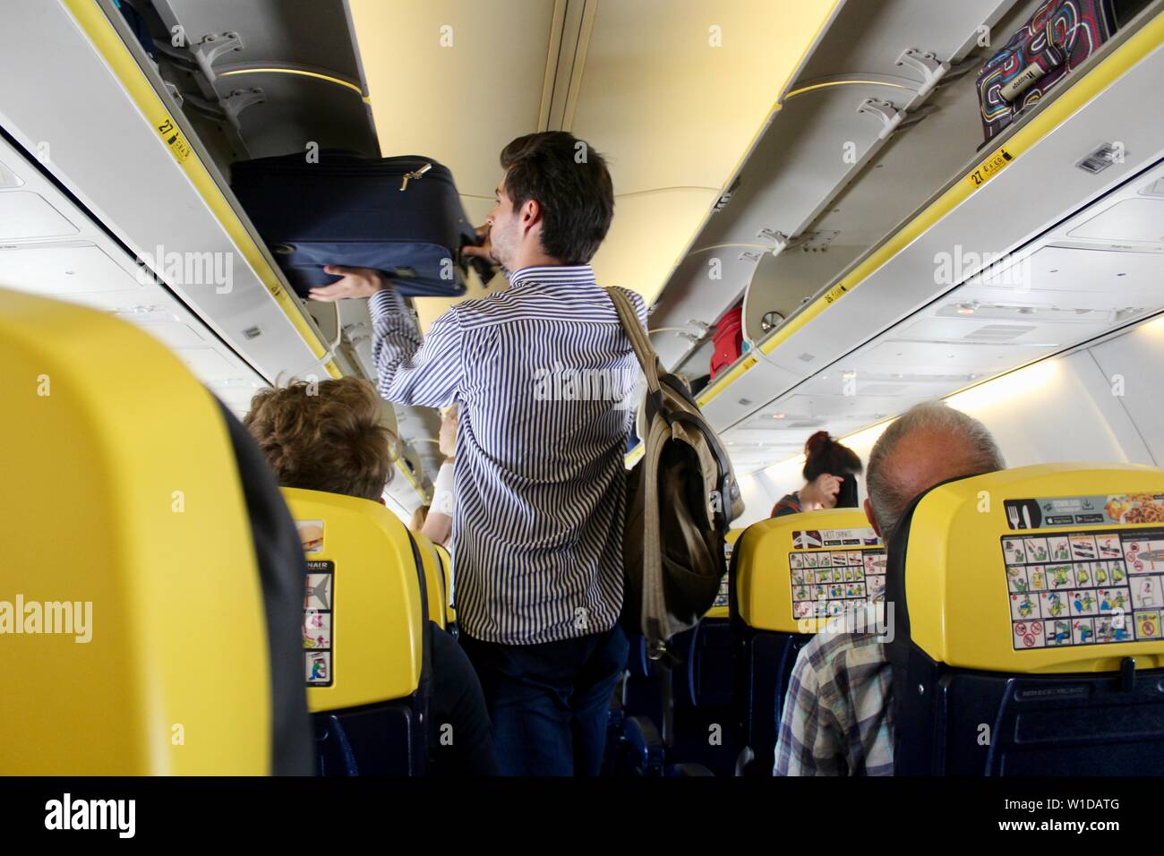 Ein Mann stellt seine Tasche in einer luftventilation auf einer Ryanair Flug Stockfoto