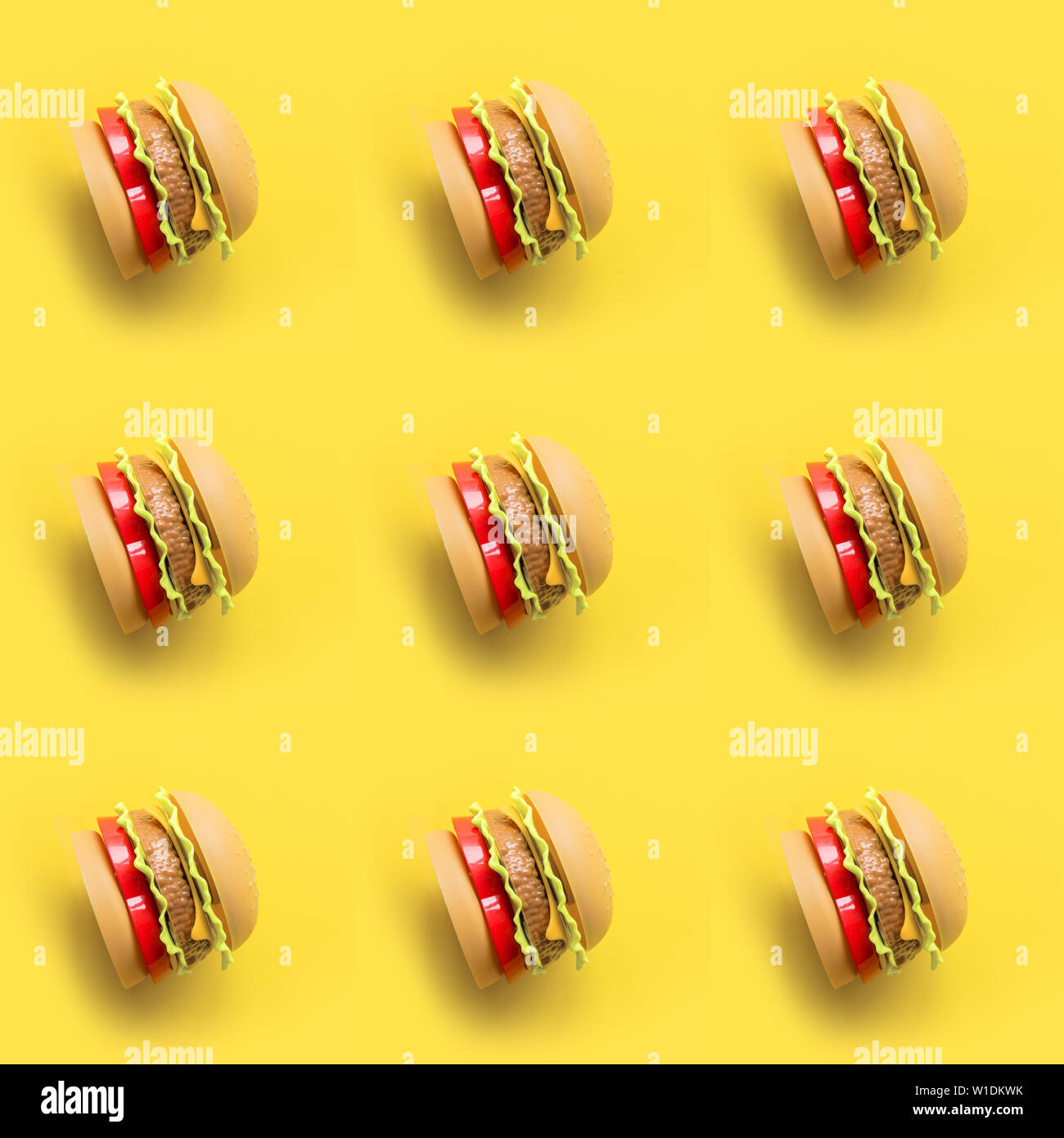 Nahtlose Muster aus Kunststoff Spielzeug der Kinder Burger mit Salat,  Tomaten, Fleisch mit auf Gelb. Begriff der künstlichen Ernährung. Ungesund.  Nicht Bio Stockfotografie - Alamy