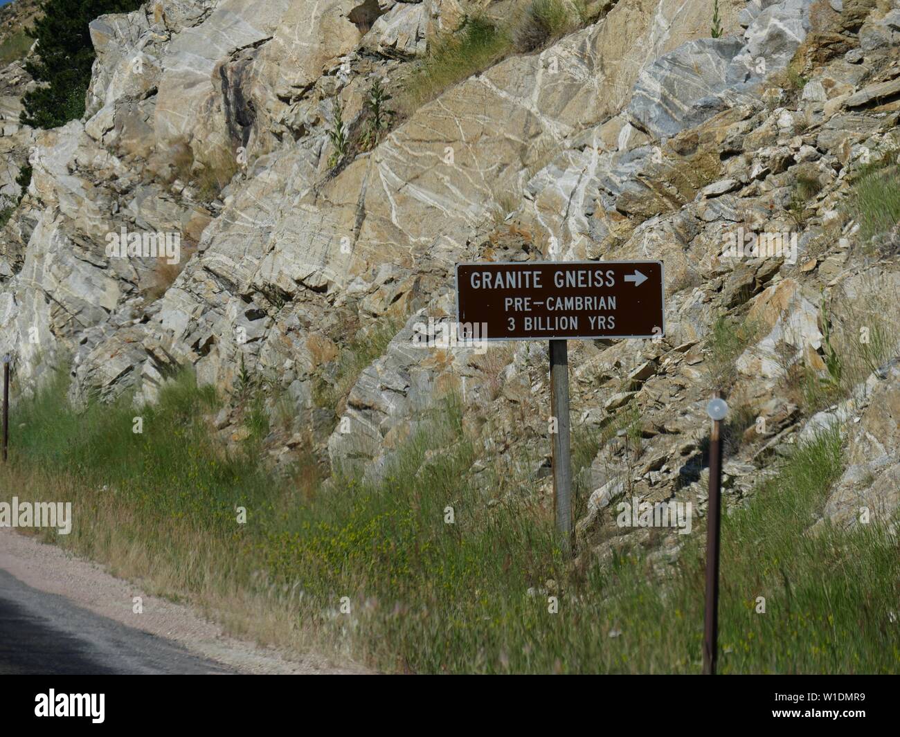 Schild am Straßenrand mit einem Pfeil, der auf Granit, Gneis, pre-Cambrian Rocks 3 Milliarden Jahren am Bighorn National Forest. Stockfoto