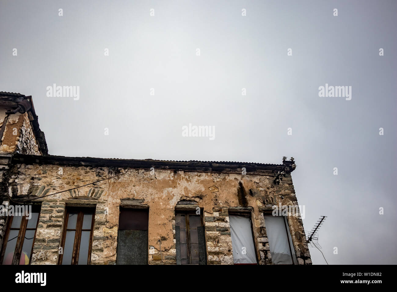 Alte griechische industrielle Gebäude im Bau mit Ziegel sichtbar, in der Innenstadt von Ioannina, Griechenland. Moody foggy Frühling Morgen, keine Menschen, Rusty TV-Antenne Silhouette Stockfoto