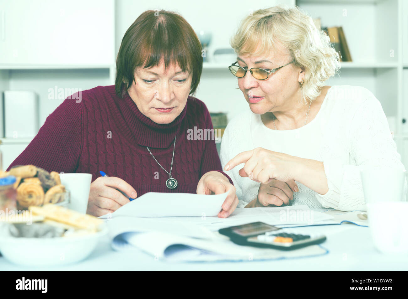 Zwei reife weibliche Freunde suchen besorgt an Papiere zu Hause Stockfoto