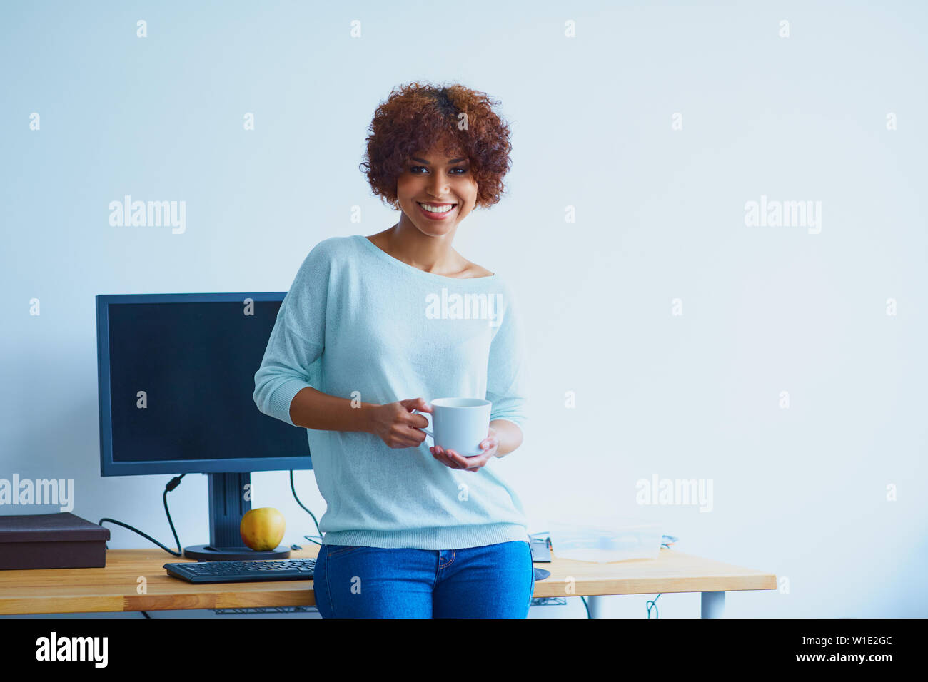 Happy Programmiererin im Büro mit Tasse Kaffee Stockfoto