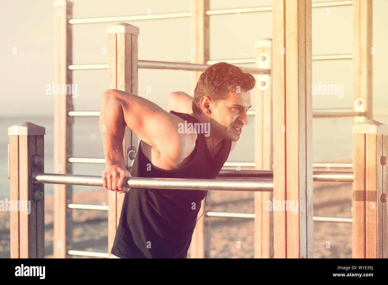 Körperlich fit Mann Training mit Musik im Freien tun Trizeps dips Am Barren Stockfoto