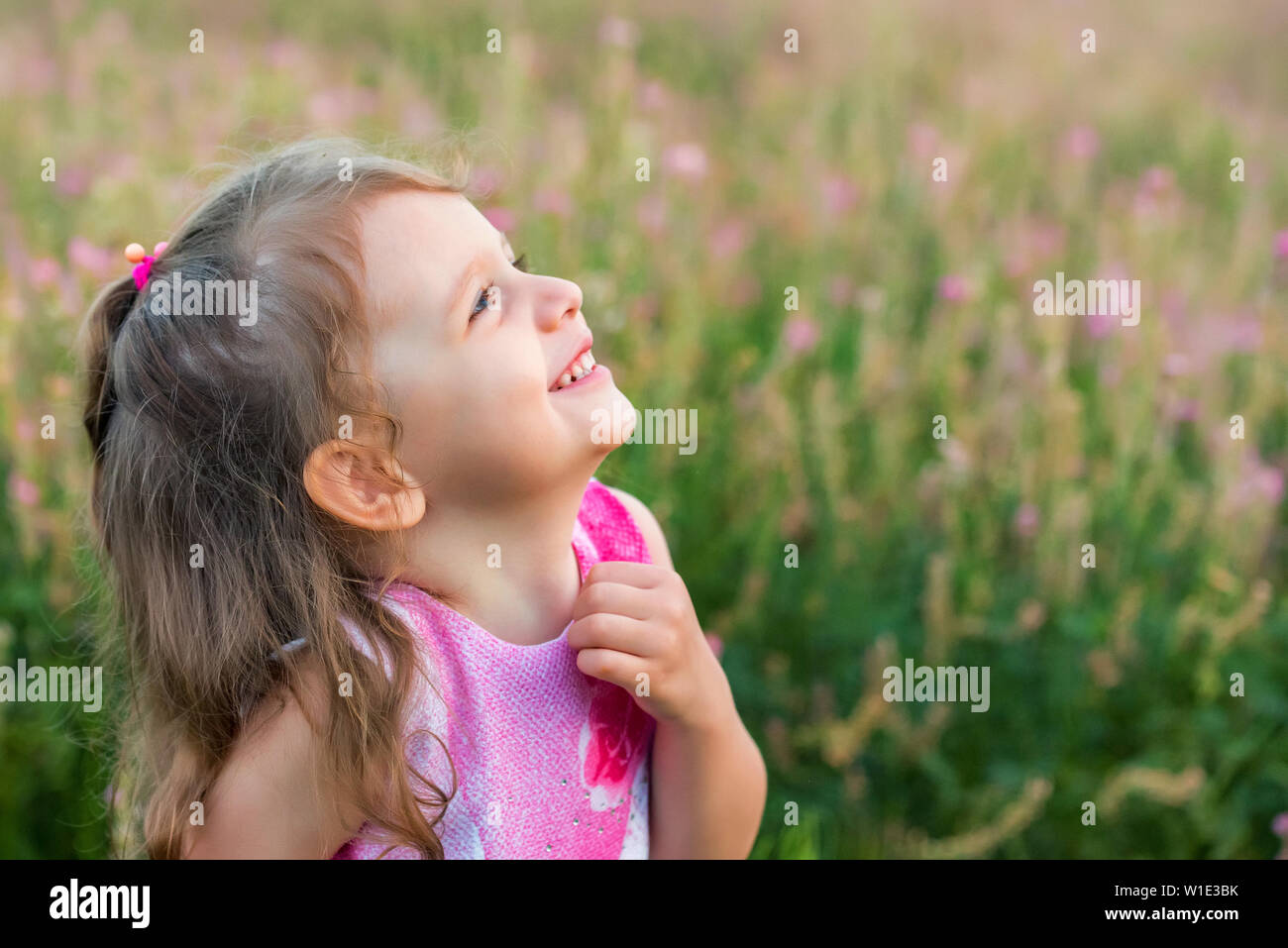 Nett lächelnden Mädchen sucht nach draußen im grünen Bereich. Kind Portrait Stockfoto