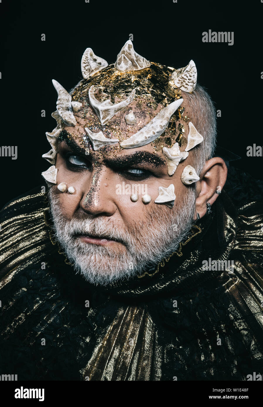 Böse Unterwelt König mit Dornen auf Gesicht und weißen Bart tragen dunkle metallische Outfit auf schwarzem Hintergrund isoliert. Daemon Kopf mit wütenden Blick, Fanta Stockfoto