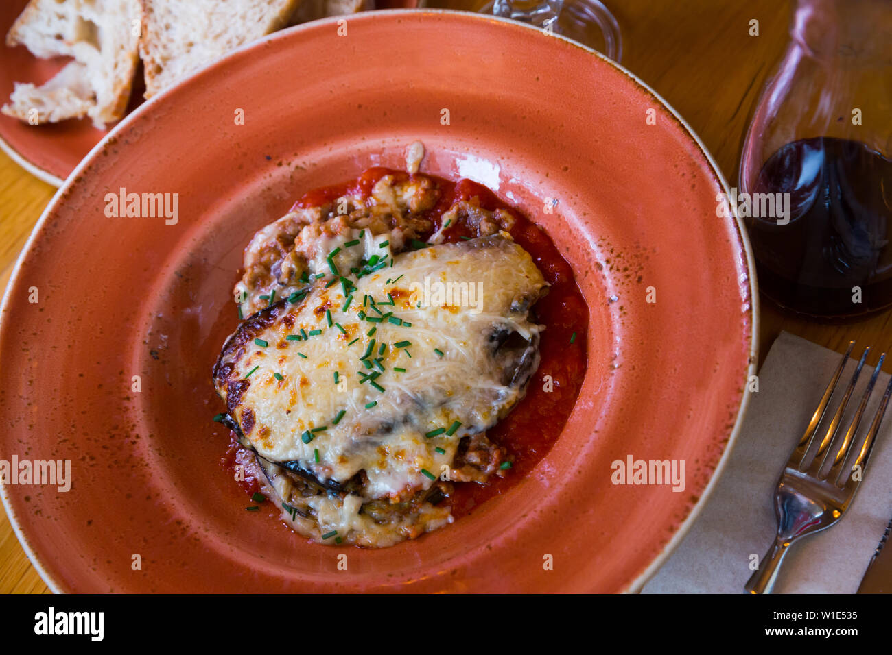Teil der leckeren Moussaka mit gehackten Schnittlauch auf Keramik Teller dekoriert Stockfoto