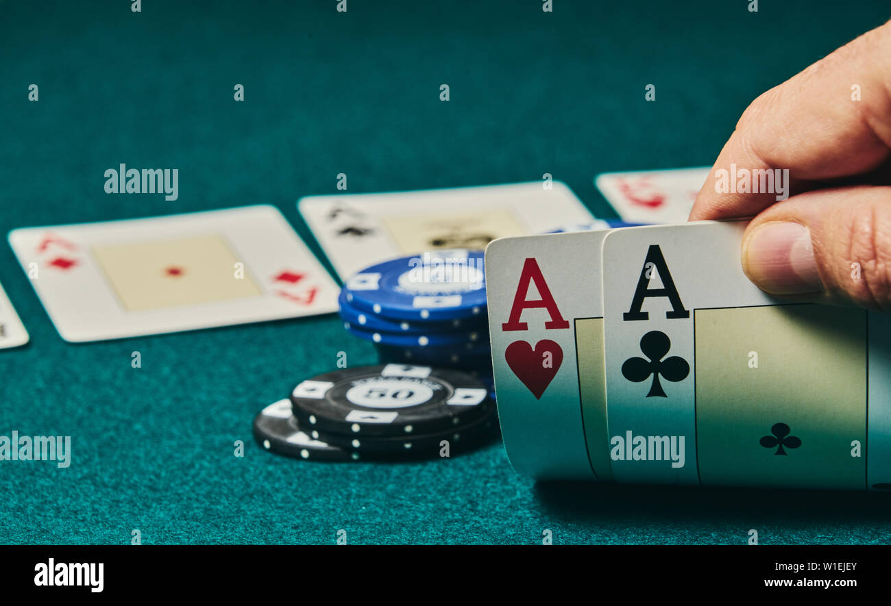 Close-up von zwei Asse in der Hand auf dem Grün spiel Matte auf der rechten Seite des Bildes statt Raum für Bearbeitung, andere Karten und poker chips zu verlassen werden Stockfoto