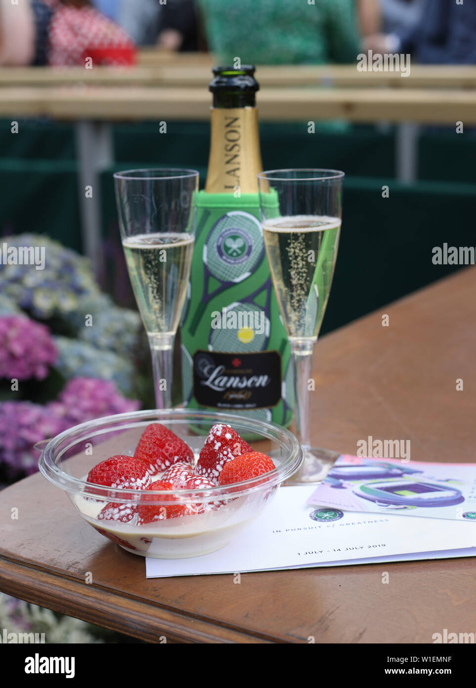 Eine Schüssel Erdbeeren und Sahne mit Gläser Champagner und Center Court Tickets an Tag zwei der Wimbledon Championships in der All England Lawn Tennis und Croquet Club, Wimbledon. Stockfoto