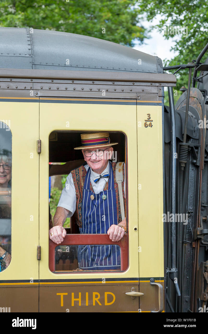 Kidderminster, Großbritannien. Juni 2019. Severn Valley Railways 'Step Back to the 40s' beginnt diesen Sommer mit einem fabelhaften Start mit kostümierten Re-Enactors, die ihre Rolle bei der Bereitstellung einer authentischen Erholung der britischen Kriegszeit des zweiten Weltkriegs spielen. Ein isolierter ranghoher Herr, der als Vintage-Metzger in Strohboater und Schürze gekleidet ist, blickt aus dem Fenster der Dampfeisenbahn. Kredit: Lee Hudson Stockfoto