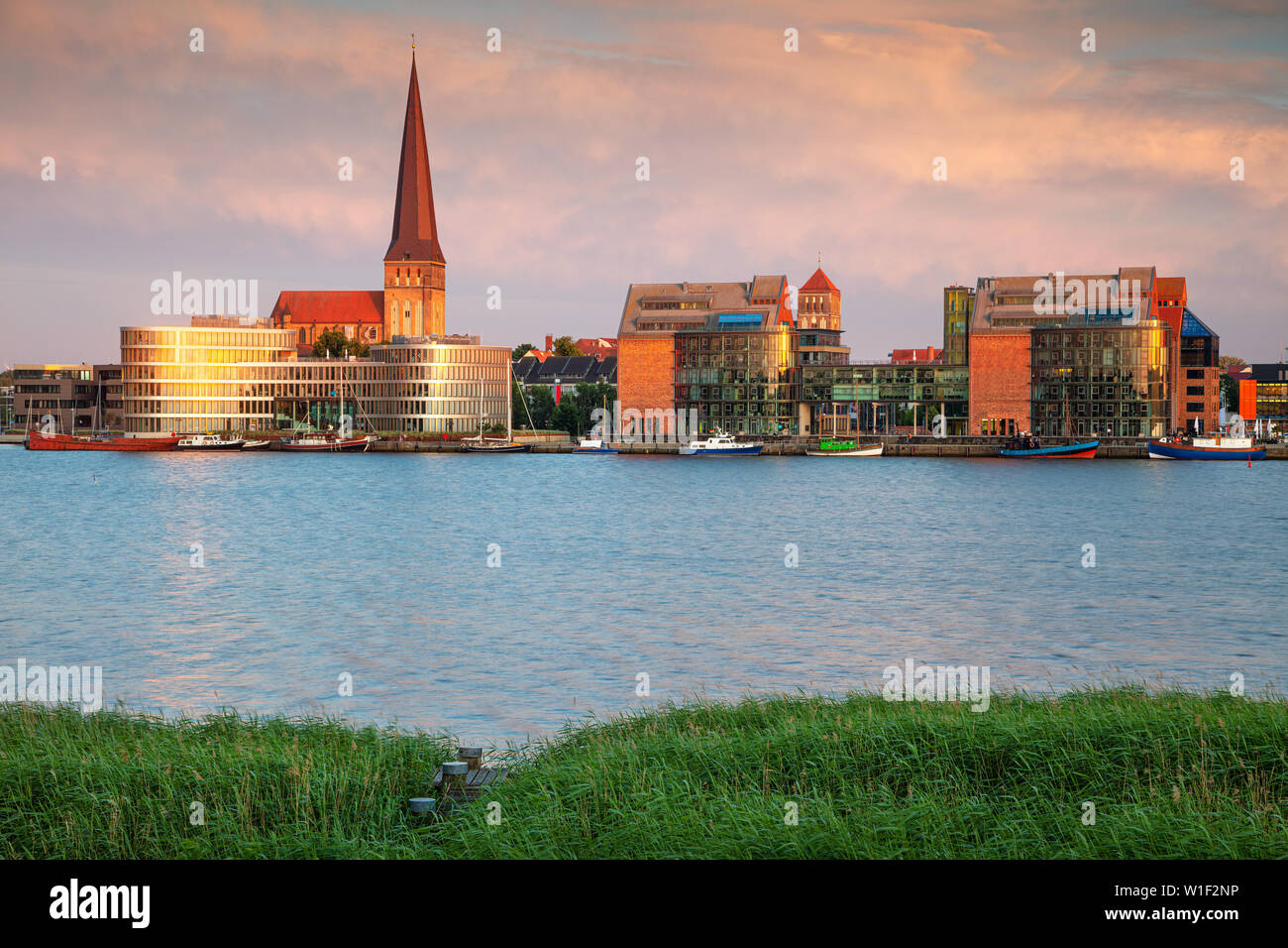 Rostock, Deutschland. Stadtbild des Rostocker Flussufers mit der Peterskirche bei Sommeruntergang. Stockfoto