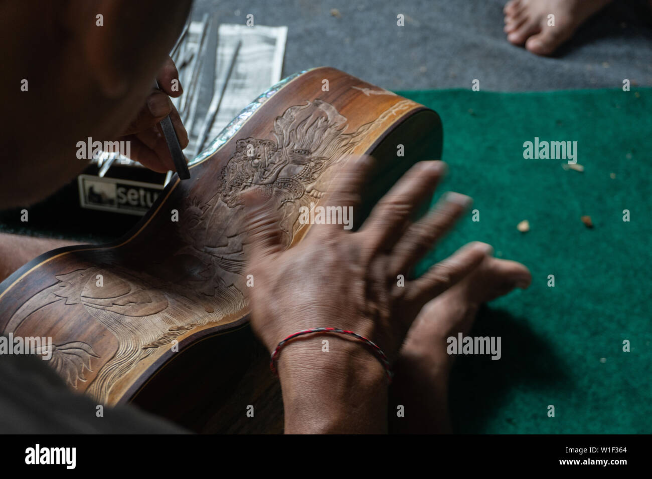Eine Gitarre Handwerker schnitzen eine klassische Gitarren aus Holz, mit balinesischen Muster, in einem hölzernen Gitarren Workshop an Guwang Dorf, Gianyar, Bali Stockfoto