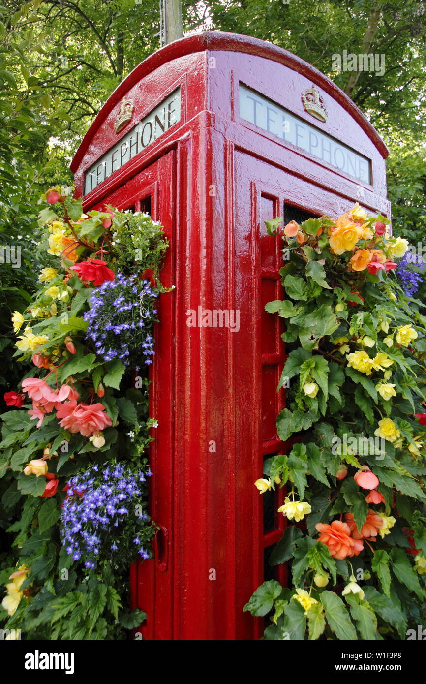 Blumentopf für Telefonhörer. Eine nicht mehr existierende Telefonbox am Straßenrand, die in einen vertikalen Garten verwandelt wurde, der in einem englischen Dorf mit Begonien und Logelien bepflanzt ist. VEREINIGTES KÖNIGREICH Stockfoto