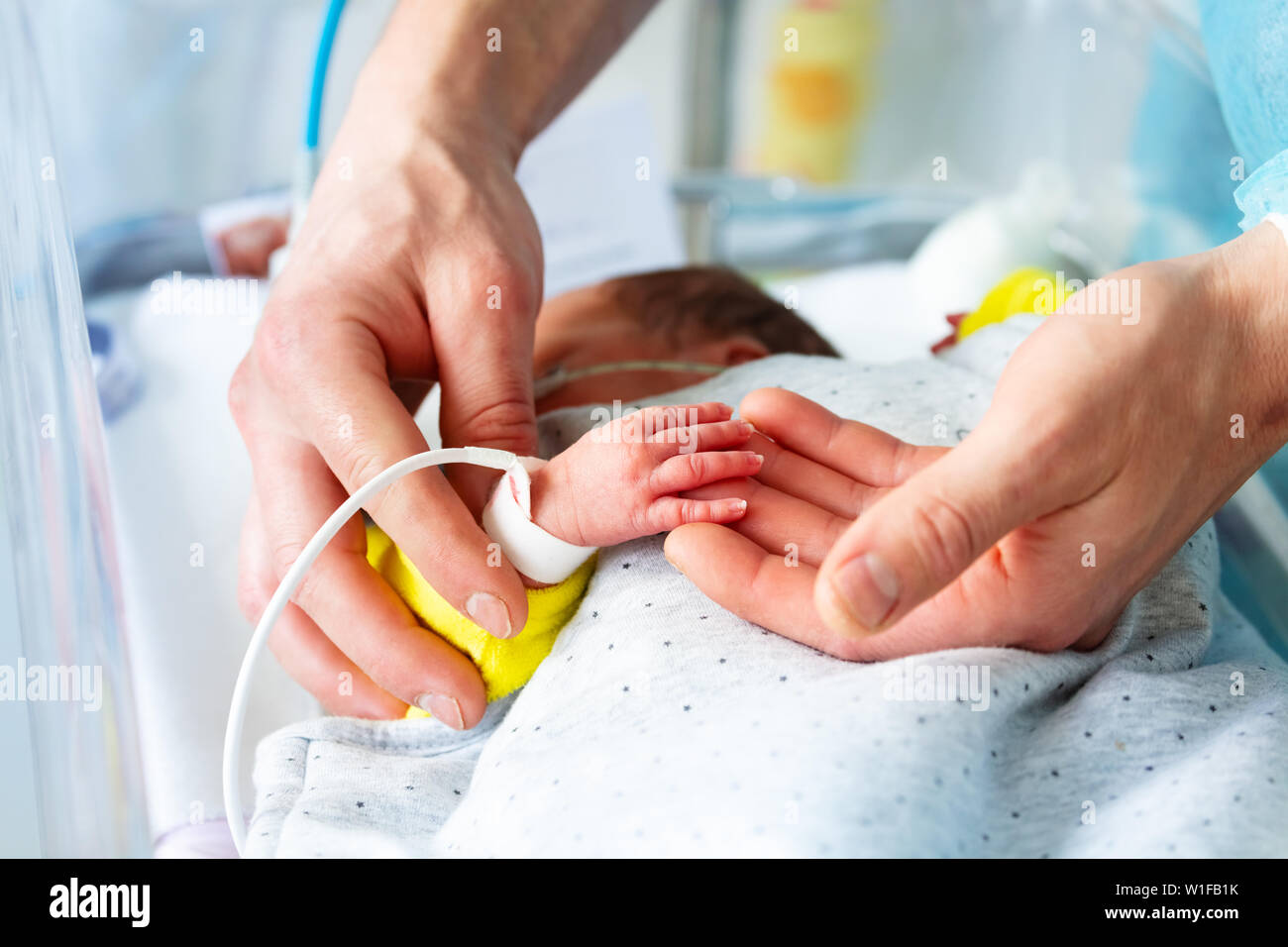 Des Vaters Hand und vorzeitiger neugeborenen Kind in ICU-Krankenhaus Zimmer mit Monitor Stockfoto