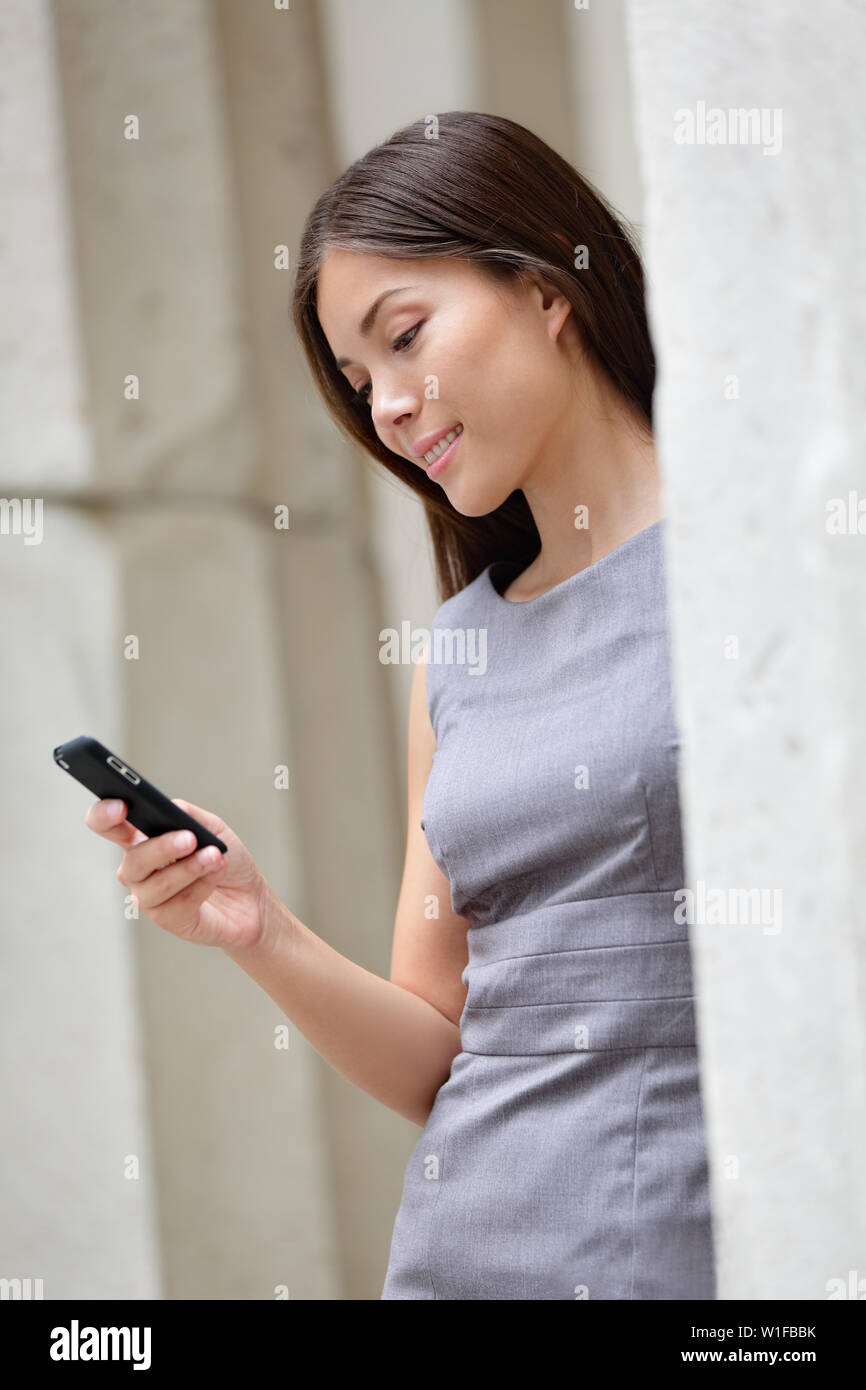 Urban Smart Casual Geschäftsfrau mit App auf dem Smartphone. Jungen asiatischen Kaukasischen erwachsenen Frau berühren smart phone mit 3g 4g App online oder sms lesen. Stockfoto