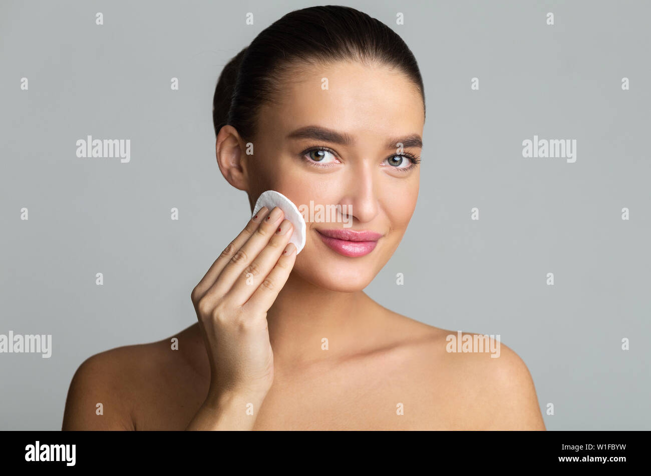 Frau Reinigung Gesicht mit Baumwolle Pad im Studio Stockfoto