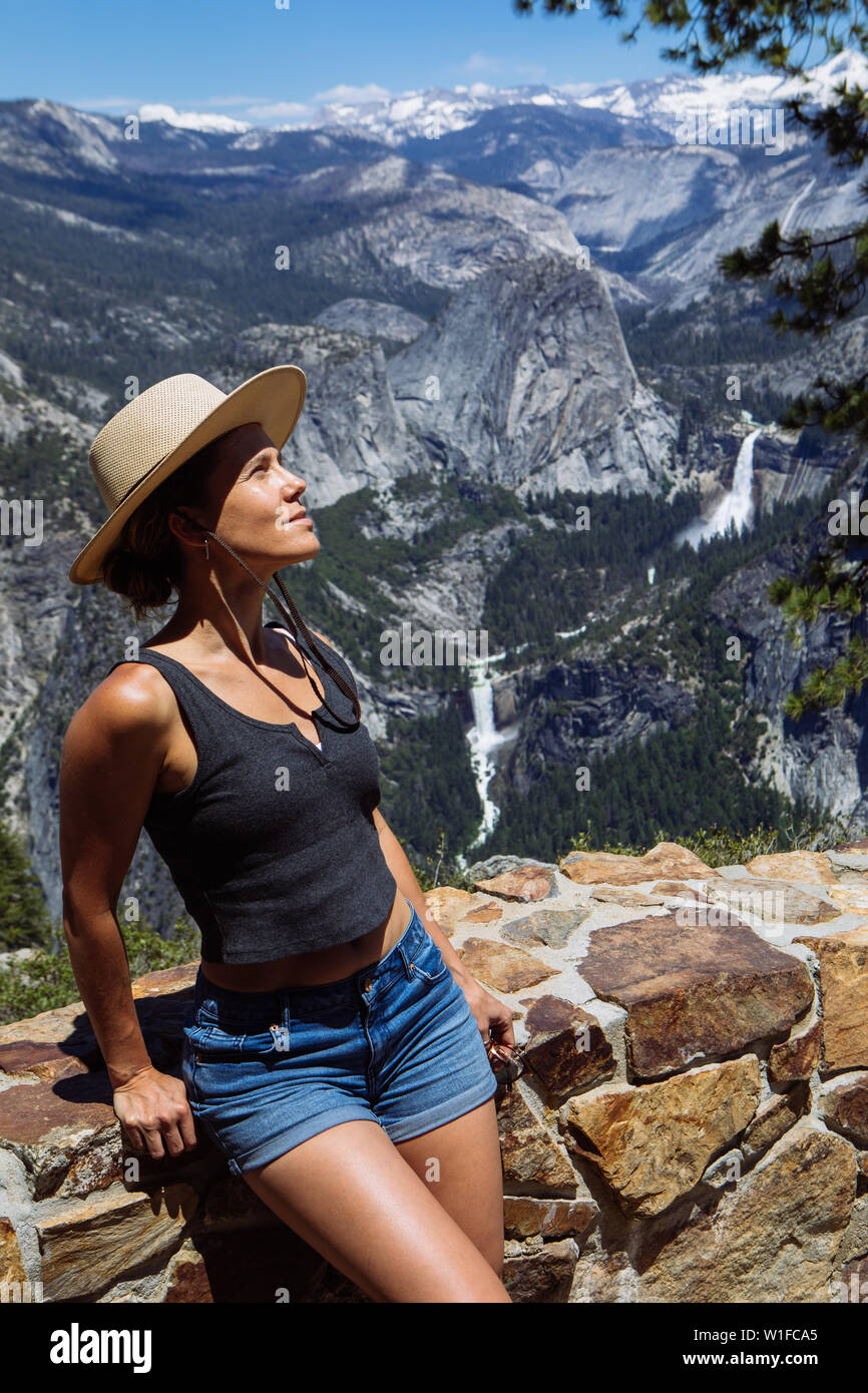 Kaukasische Frau aus Touristen in den Dreißigern posiert in Glacier Point mit Nevada Fall im Yosemite National Park, Kalifornien, USA Stockfoto