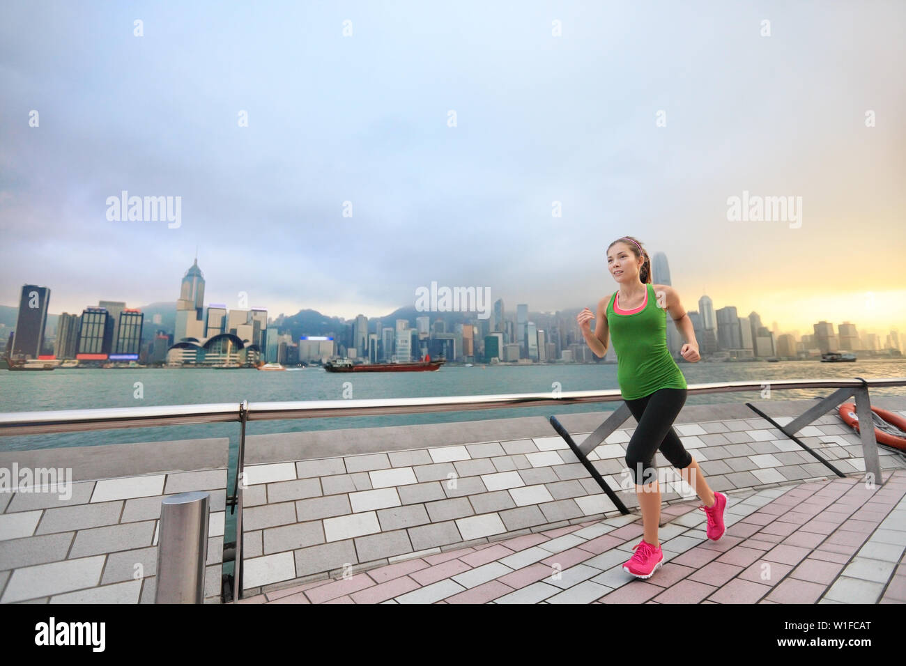 Sport Frau Läufer in Hong Kong Skyline läuft. Asiatische chinesische fitness Sportler joggen training Leben gesunder Lebensstil auf Tsim Sha Tsui Promenade und Avenue der Stars in den Victoria Harbour und Kowloon. Stockfoto