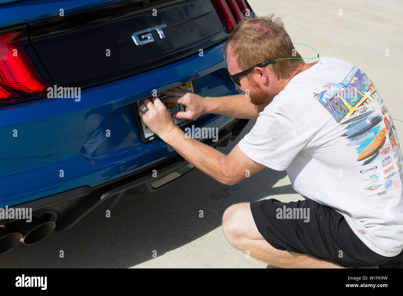 Ein Mann legt eine staatliche Lizenz Platte bei der Lieferung eines neuen Blue 2019 Ford Mustang GT an seinen Besitzer in Palm City, Florida, USA. Stockfoto