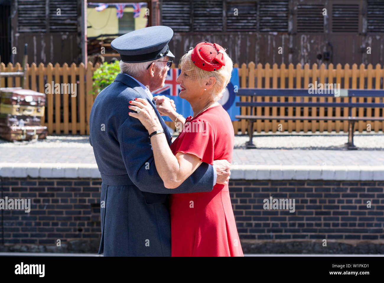 Kidderminster, Großbritannien. Juni 2019. Severn Valley Railways 'Step Back to the 40's' startet dieses Sommerwochenende mit kostümierten Re-Enactors, die ihre Rolle bei der Bereitstellung einer authentischen Erholung von Wartime Britain spielen. Ein elegant gekleidetes, glückliches Ehepaar aus den vierziger Jahren tanzt zusammen auf dem Bahnsteig eines alten Bahnhofs in der Morgensonne. Kredit: Lee Hudson Stockfoto