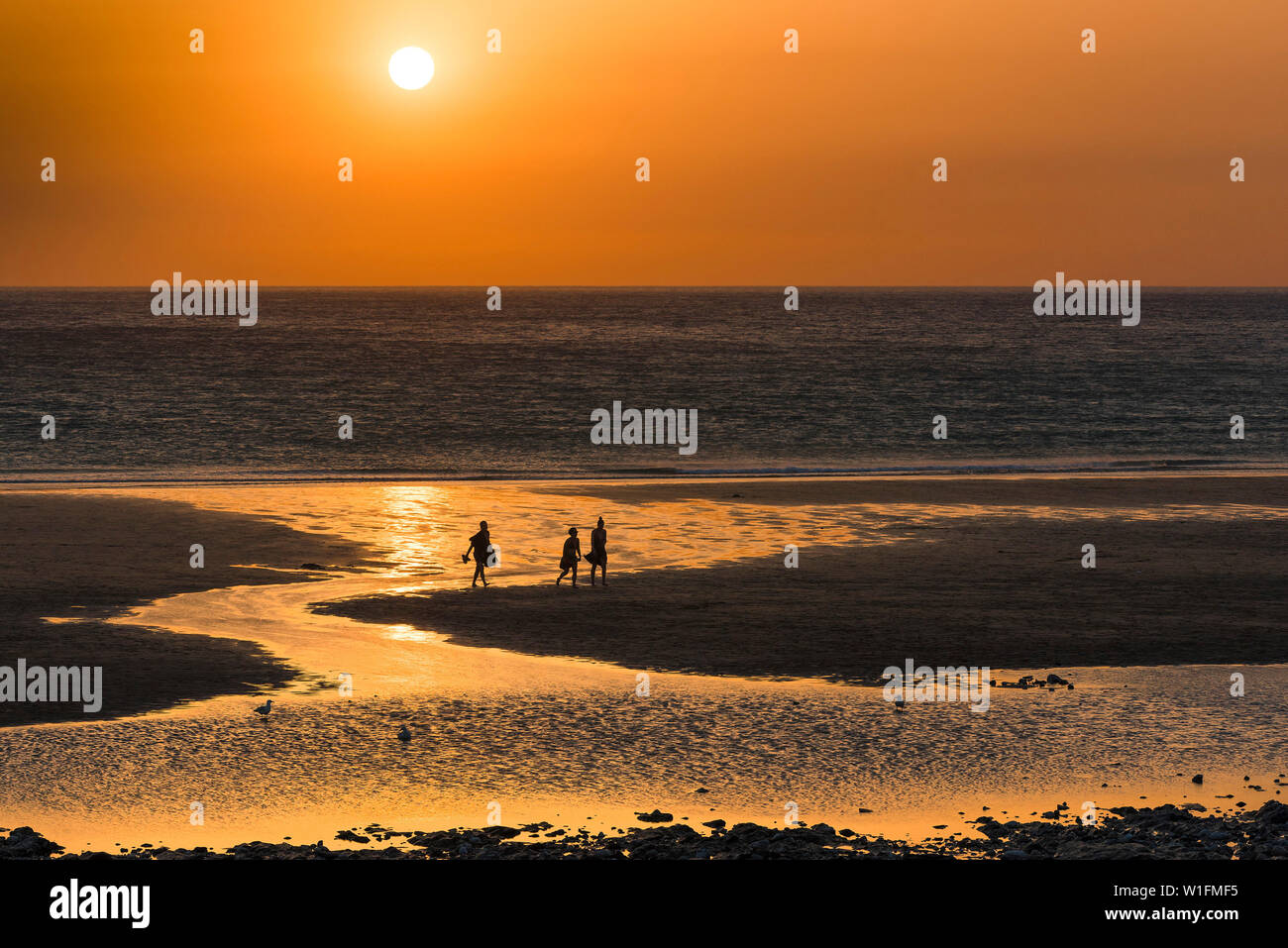 Menschen in Silhouette als einen wunderschönen Sonnenuntergang setzt auf den Fistral Beach in Newquay in Cornwall gesehen. Stockfoto