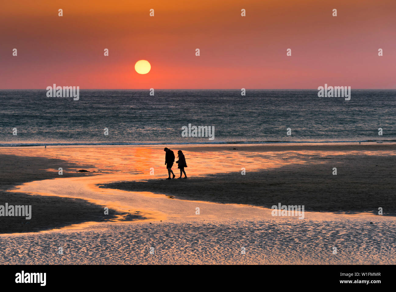 Menschen in Silhouette als einen wunderschönen Sonnenuntergang setzt auf den Fistral Beach in Newquay in Cornwall gesehen. Stockfoto