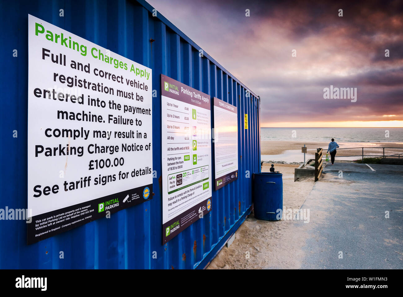 Parken Informationen Hinweise auf der Seite der Blau Metall Container leuchtet durch das warme Licht der untergehenden Sonne auf den Fistral Bay in Newqiau in Cornwall. Stockfoto