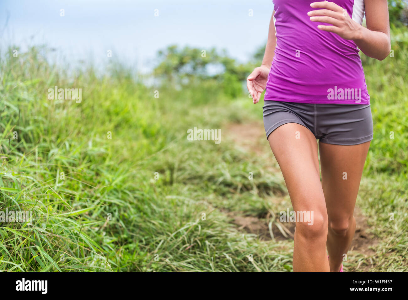 Gesunde, aktive Frau Läufer laufen im Freien gras natur park Trail weg. Midsection untere Körper des Mädchens Athlet Training cardio. Feminine Gesundheitsfragen: Menstruation Schmerzen, Magen problem. Stockfoto