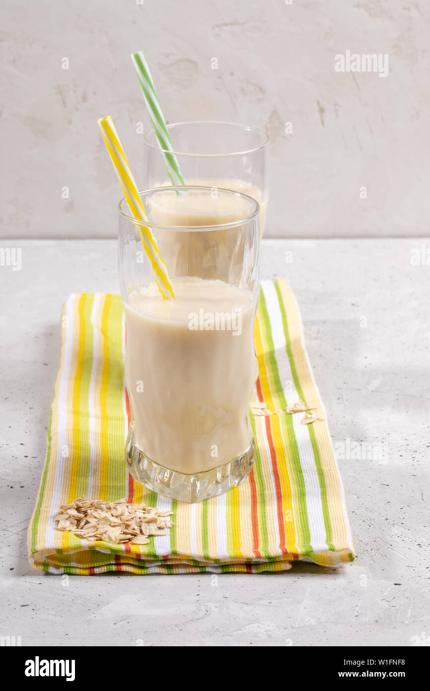 Zwei Gläser mit hafermilch mit Trinkhalme auf gelb-grün Handtuch für die Küche. Stockfoto