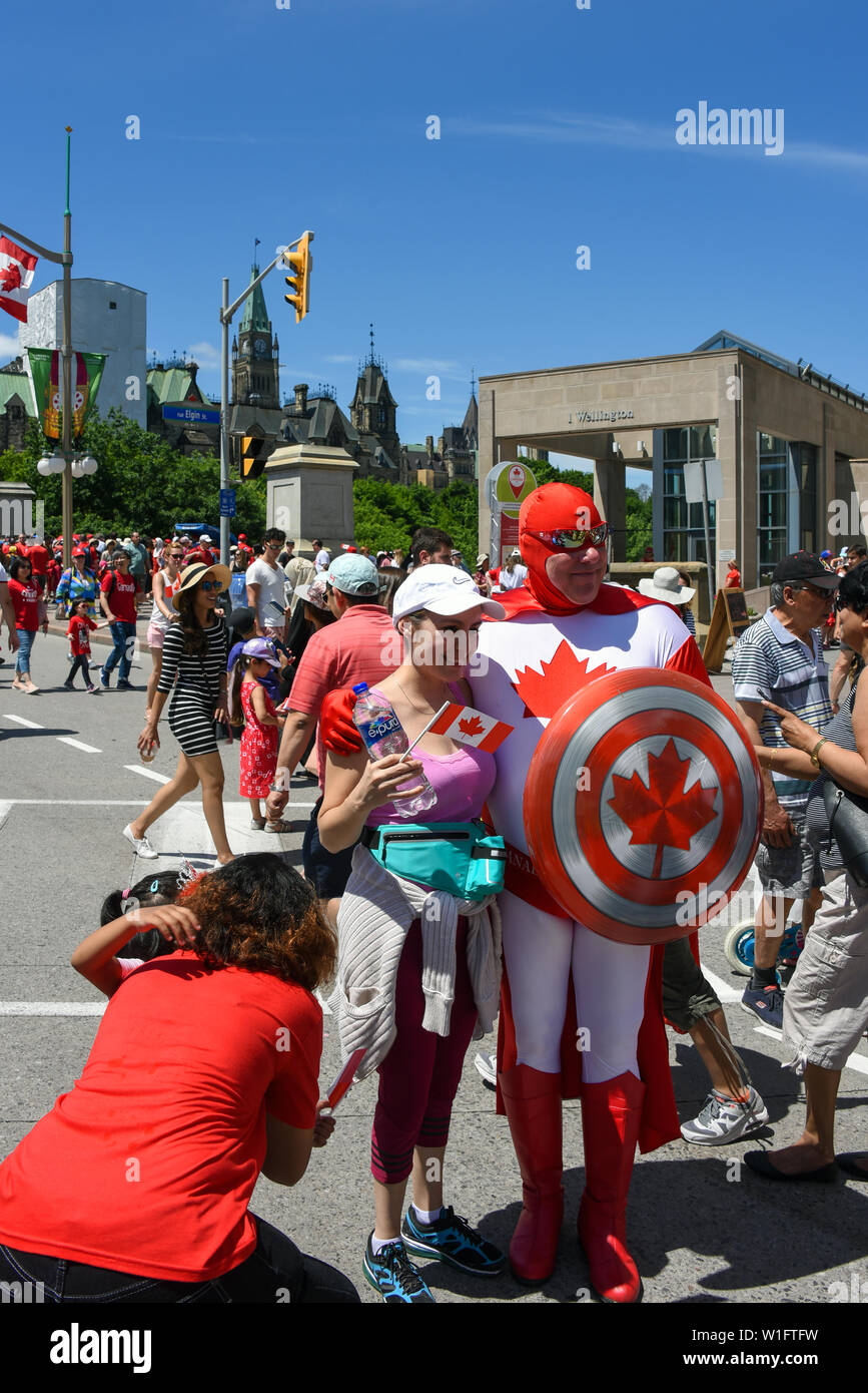Ottawa, Kanada - Juli 2019: Frau posiert für Bild mit Mann in einem kanadischen Superhelden Outfit gekleidet während der jährlichen Canada Day Feier in der Ca Stockfoto